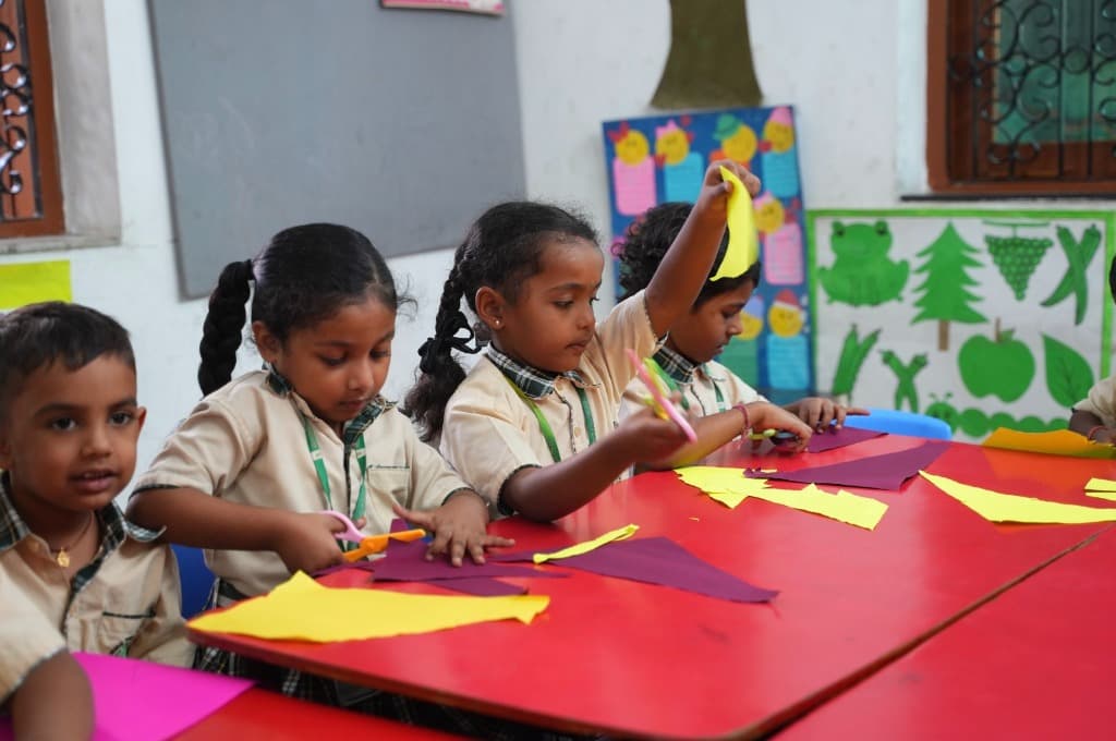 Children cutting shapes out of paper inside the classroom