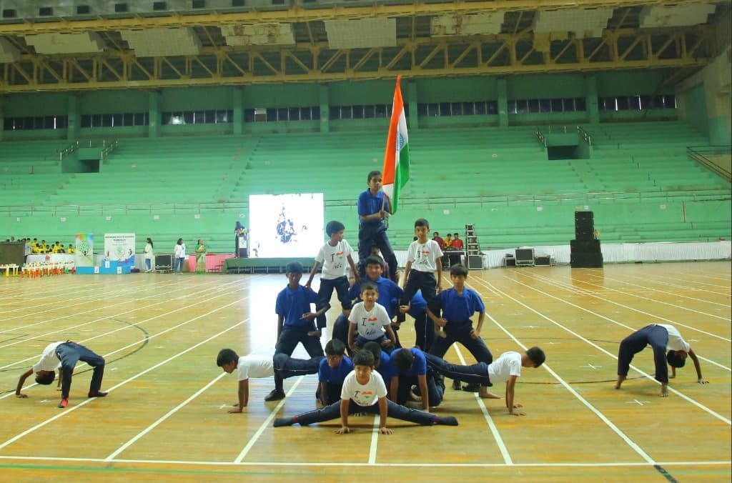 Students performing acrobatic physical pyramid with flag
