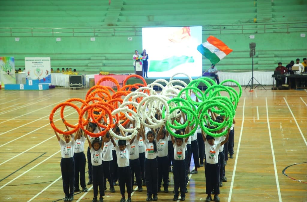Children in white t-shirts holding up orange, white, and green floral rings